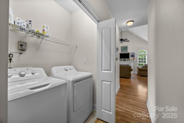 laundry room with laundry area, a ceiling fan, washing machine and dryer, light wood-type flooring, and baseboards