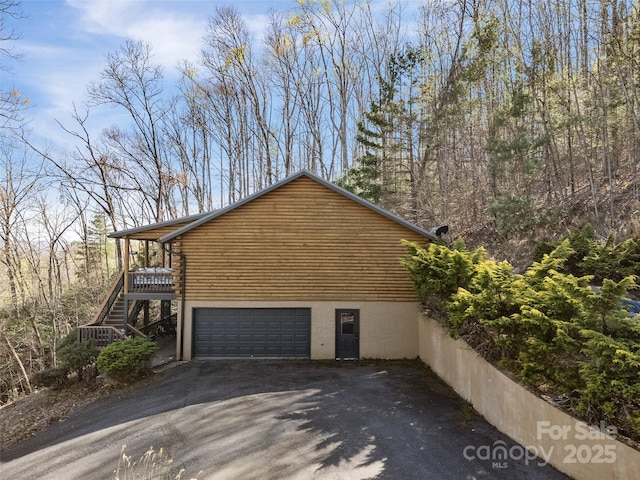 view of home's exterior featuring stairway, an attached garage, driveway, and log siding