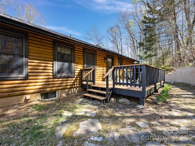 exterior space with faux log siding, fence, and a deck