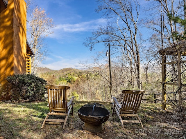 view of yard featuring an outdoor fire pit and a wooded view