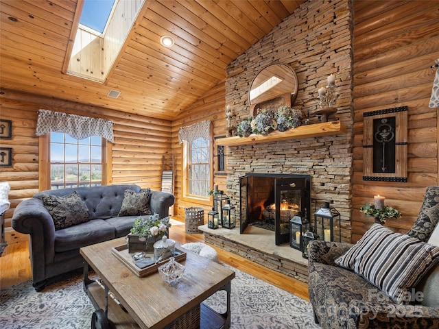 living area featuring hardwood / wood-style floors, a stone fireplace, a wealth of natural light, and wood ceiling