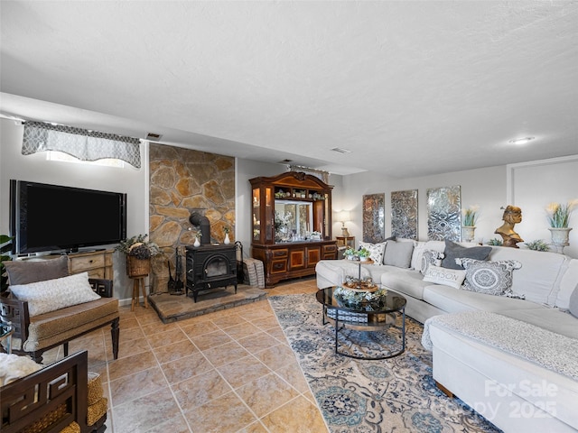 living area featuring tile patterned floors, visible vents, and a wood stove