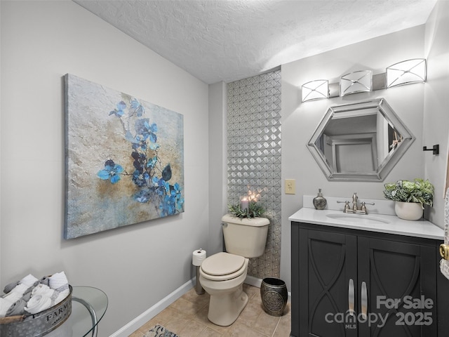 bathroom featuring tile patterned floors, toilet, vanity, baseboards, and a textured ceiling