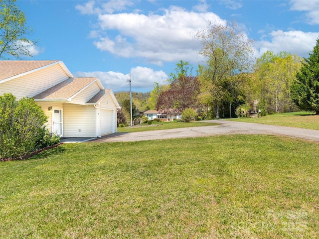 view of yard with an attached garage and driveway