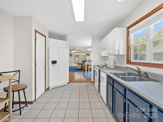 kitchen with blue cabinets, white cabinets, a sink, white appliances, and light countertops