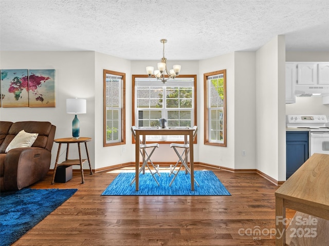 dining space featuring an inviting chandelier, wood finished floors, a textured ceiling, and baseboards