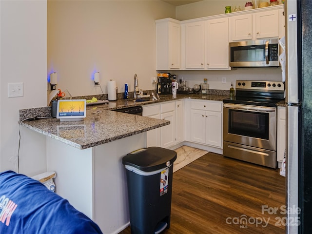 14727 Choate Cir Unit 2, Charlotte, NC 28273 - kitchen with a sink, a peninsula, dark wood-type flooring, white cabinetry, and appliances with stainless steel finishes