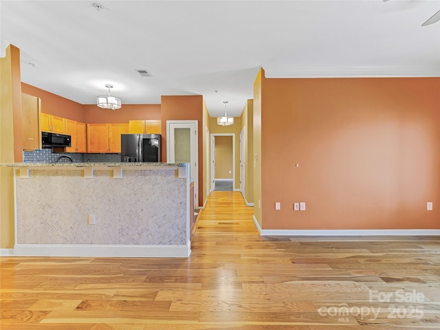 kitchen featuring baseboards, visible vents, light wood-style floors, fridge with ice dispenser, and black microwave