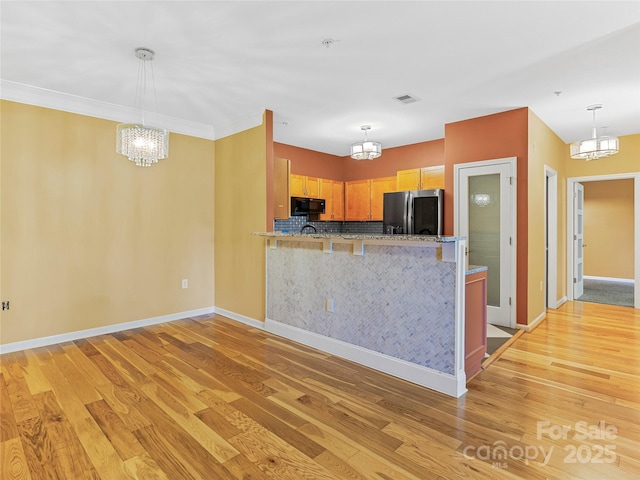 kitchen featuring smart refrigerator, black microwave, a notable chandelier, and light wood-style flooring