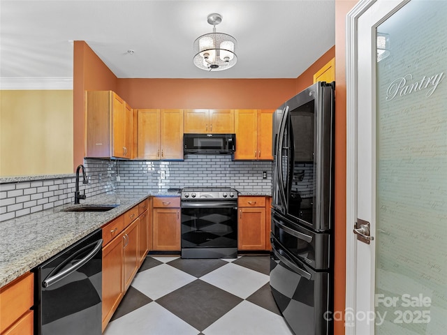 kitchen featuring dark floors, a sink, light stone countertops, decorative backsplash, and black appliances