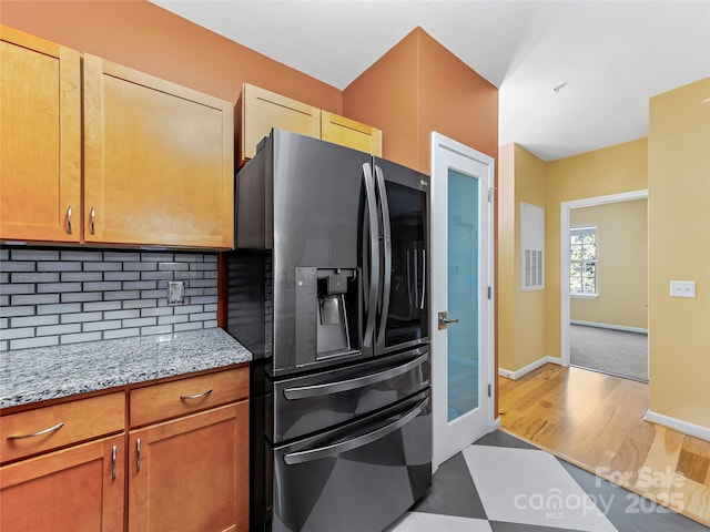 kitchen featuring wood finished floors, decorative backsplash, stainless steel fridge with ice dispenser, baseboards, and light stone countertops