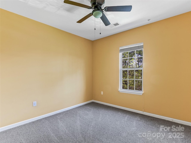 carpeted empty room with baseboards, a ceiling fan, and visible vents