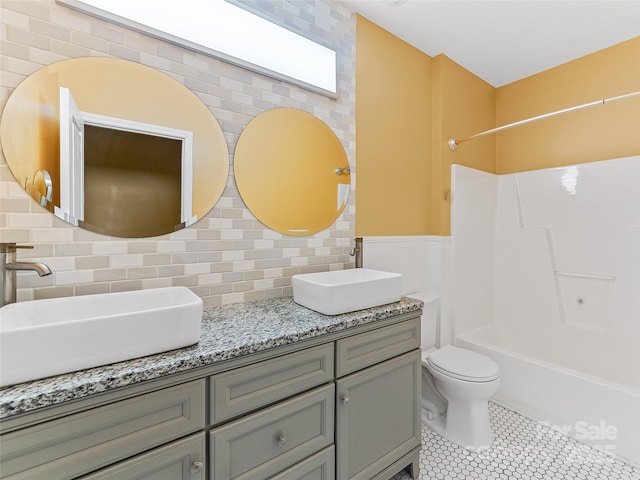 bathroom with backsplash, double vanity, shower / tub combination, and a sink
