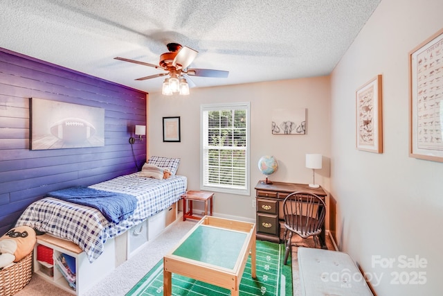 bedroom with a textured ceiling, wooden walls, and a ceiling fan