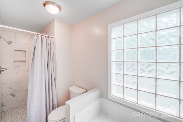 bathroom featuring a tile shower and toilet
