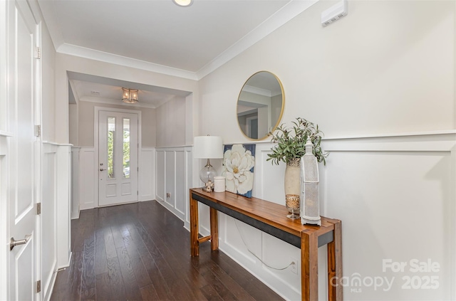 foyer featuring hardwood / wood-style floors, a decorative wall, crown molding, and a wainscoted wall
