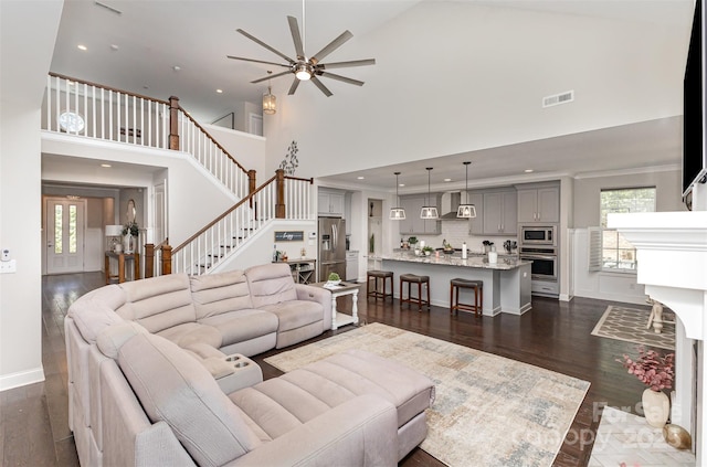 living room with stairway, a ceiling fan, a towering ceiling, dark wood-type flooring, and recessed lighting