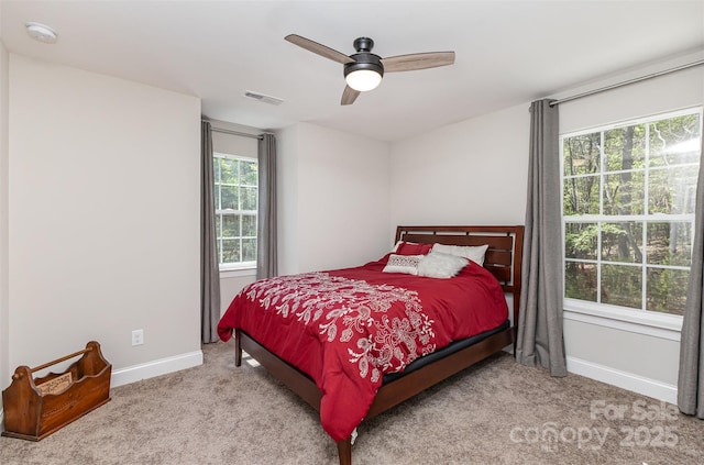 carpeted bedroom with baseboards, a ceiling fan, multiple windows, and visible vents