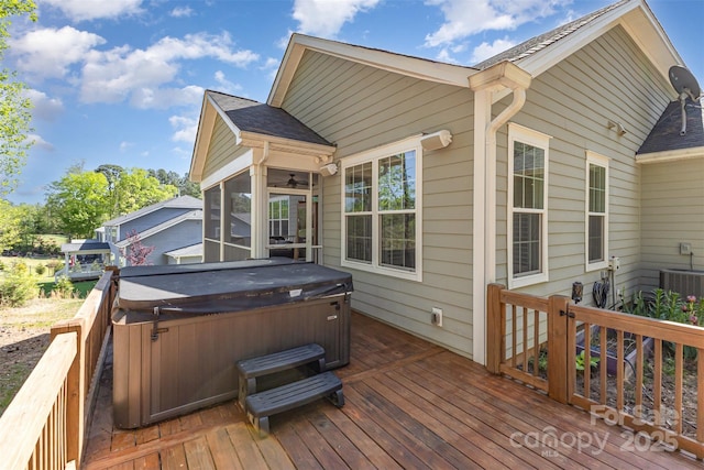 deck featuring a sunroom, a hot tub, a ceiling fan, and cooling unit