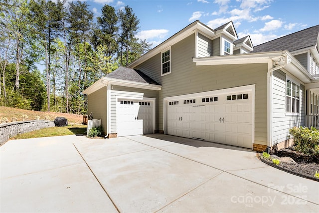 view of property exterior with an attached garage and driveway