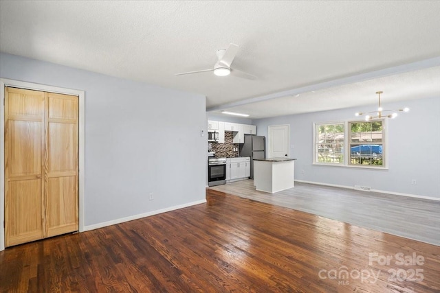 unfurnished living room featuring baseboards, wood finished floors, visible vents, and ceiling fan with notable chandelier