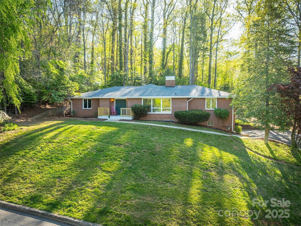 31 Pheasant Dr, Asheville, NC 28803 - single story home featuring brick siding, a view of trees, a front lawn, and a chimney