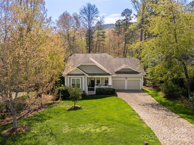 single story home featuring a garage, a front lawn, decorative driveway, roof with shingles, and a porch