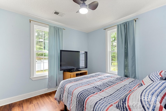 814 Columbia Dr, Chester, SC 29706 - bedroom featuring wood finished floors, multiple windows, baseboards, a ceiling fan, and a textured ceiling