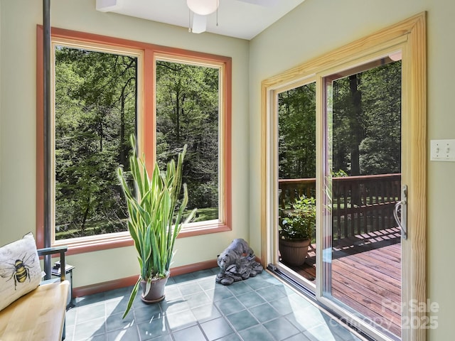 doorway featuring baseboards, tile patterned flooring, and a ceiling fan