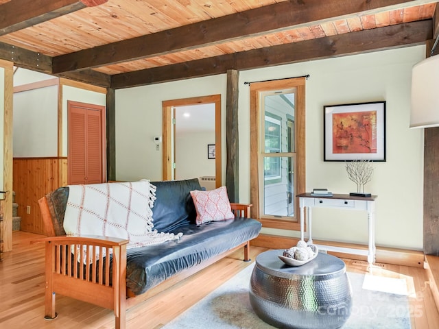 living room with wooden walls, wood ceiling, beamed ceiling, and wood finished floors