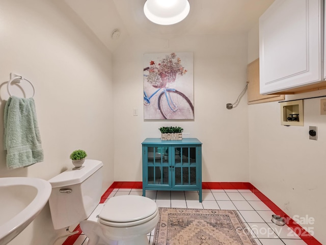 half bath featuring tile patterned flooring, a sink, and toilet
