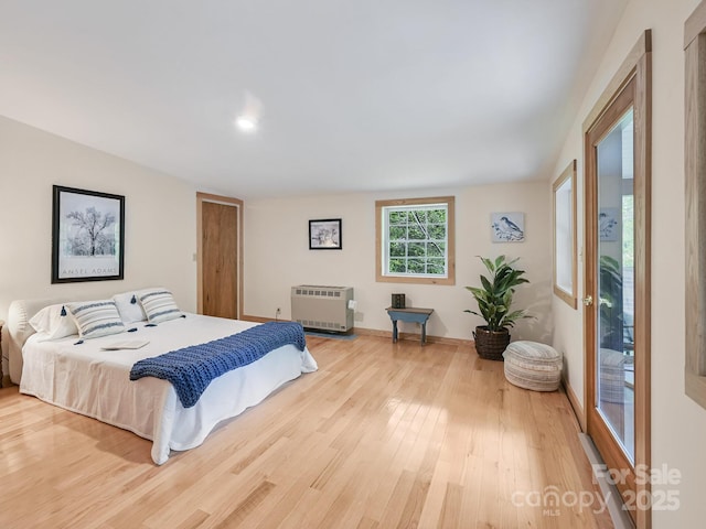 bedroom with light wood-style floors, baseboards, and heating unit