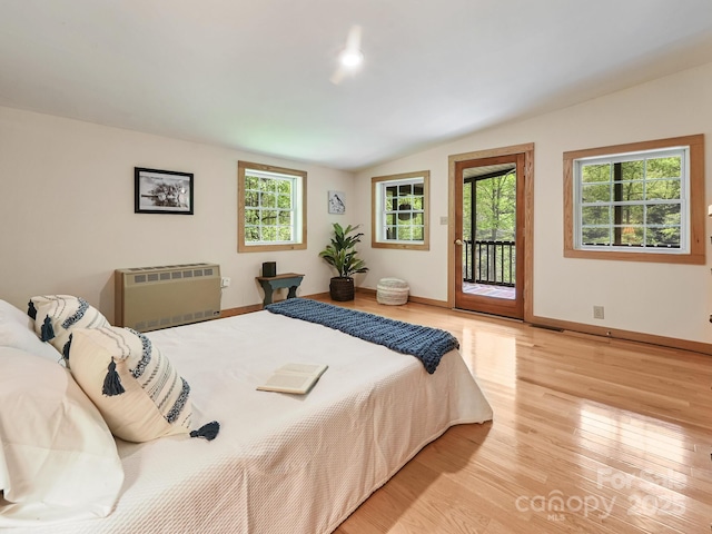 bedroom with access to outside, baseboards, heating unit, wood finished floors, and lofted ceiling