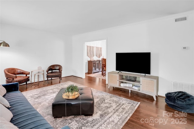 living room with ornamental molding, wood finished floors, and visible vents