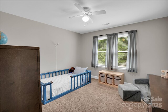 carpeted bedroom with baseboards, a ceiling fan, and visible vents