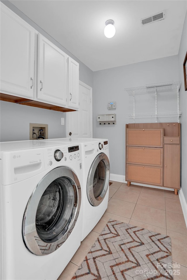 laundry area featuring visible vents, baseboards, light tile patterned flooring, separate washer and dryer, and cabinet space