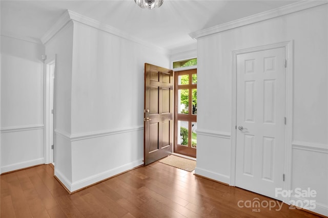 foyer entrance featuring hardwood / wood-style flooring, baseboards, and crown molding