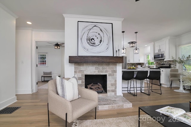 2138 Revolution Park Dr, Charlotte, NC 28208 - living room with a ceiling fan, crown molding, light wood-type flooring, recessed lighting, and a fireplace