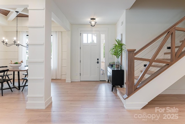 foyer with a notable chandelier, baseboards, stairs, and light wood-type flooring