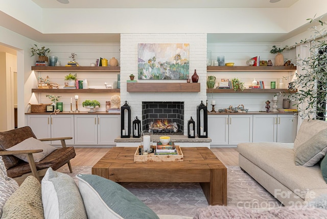 living area featuring a brick fireplace and light wood-type flooring