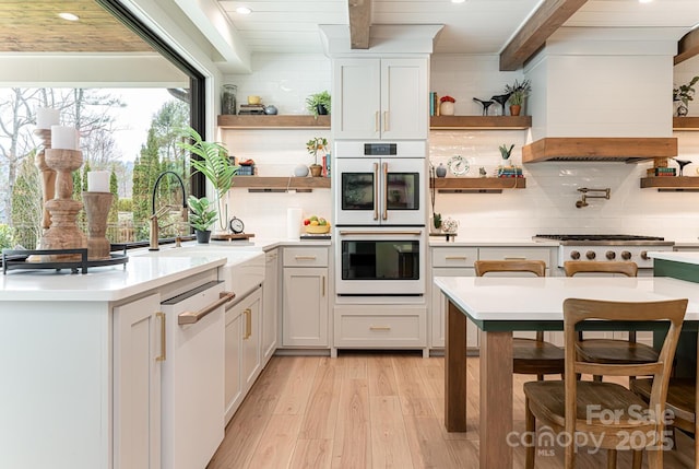 kitchen with beamed ceiling, open shelves, white appliances, and light wood-style flooring