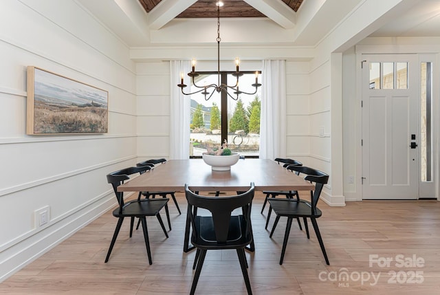 dining area with beam ceiling, an inviting chandelier, light wood-style floors, and a decorative wall