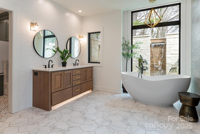 full bathroom with double vanity, a sink, recessed lighting, and a freestanding bath