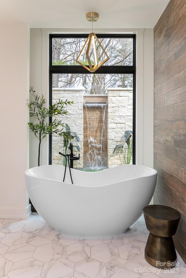 bathroom featuring marble finish floor, baseboards, and a freestanding bath