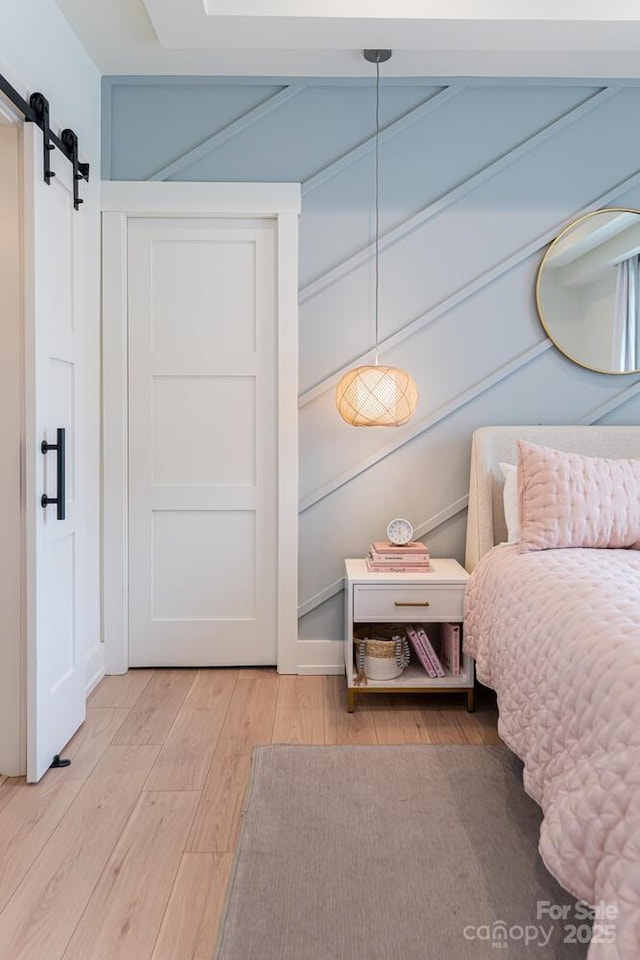 bedroom with a barn door and light wood-style flooring