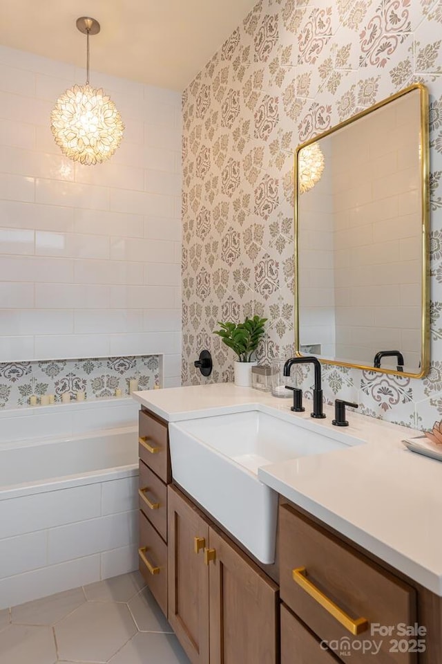full bathroom featuring wallpapered walls, tile patterned flooring, vanity, tiled bath, and a chandelier