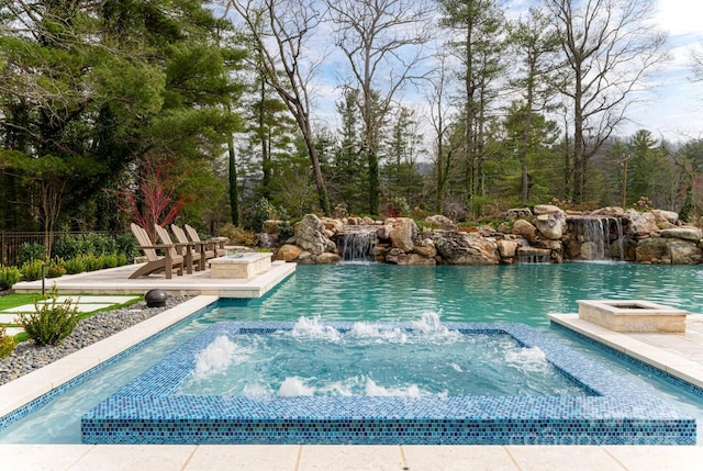 pool with a patio, an in ground hot tub, and an outdoor fire pit