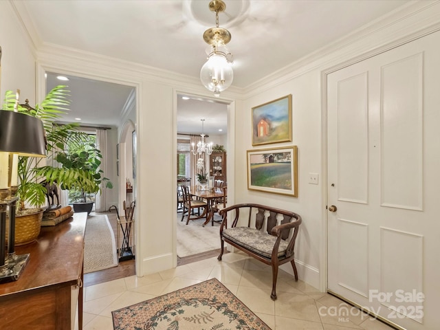 foyer featuring a chandelier, crown molding, baseboards, and light tile patterned floors