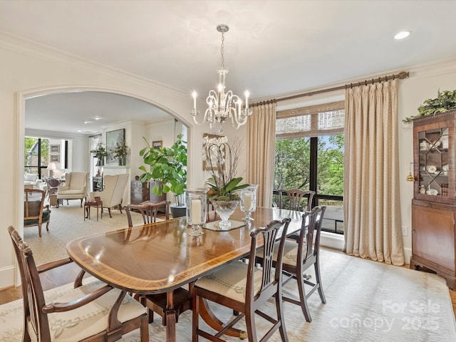 dining area featuring arched walkways, plenty of natural light, crown molding, and an inviting chandelier