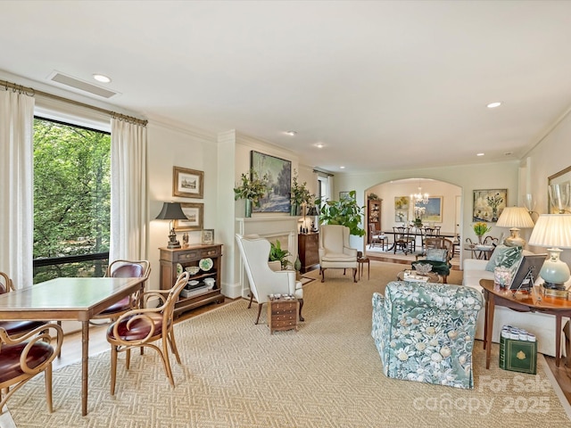 living room featuring crown molding, arched walkways, an inviting chandelier, visible vents, and recessed lighting